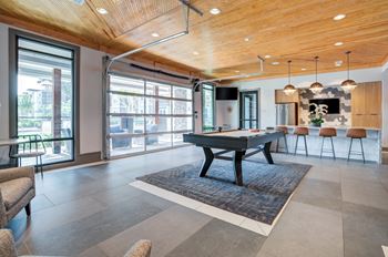 A game room with a pool table in the middle of it